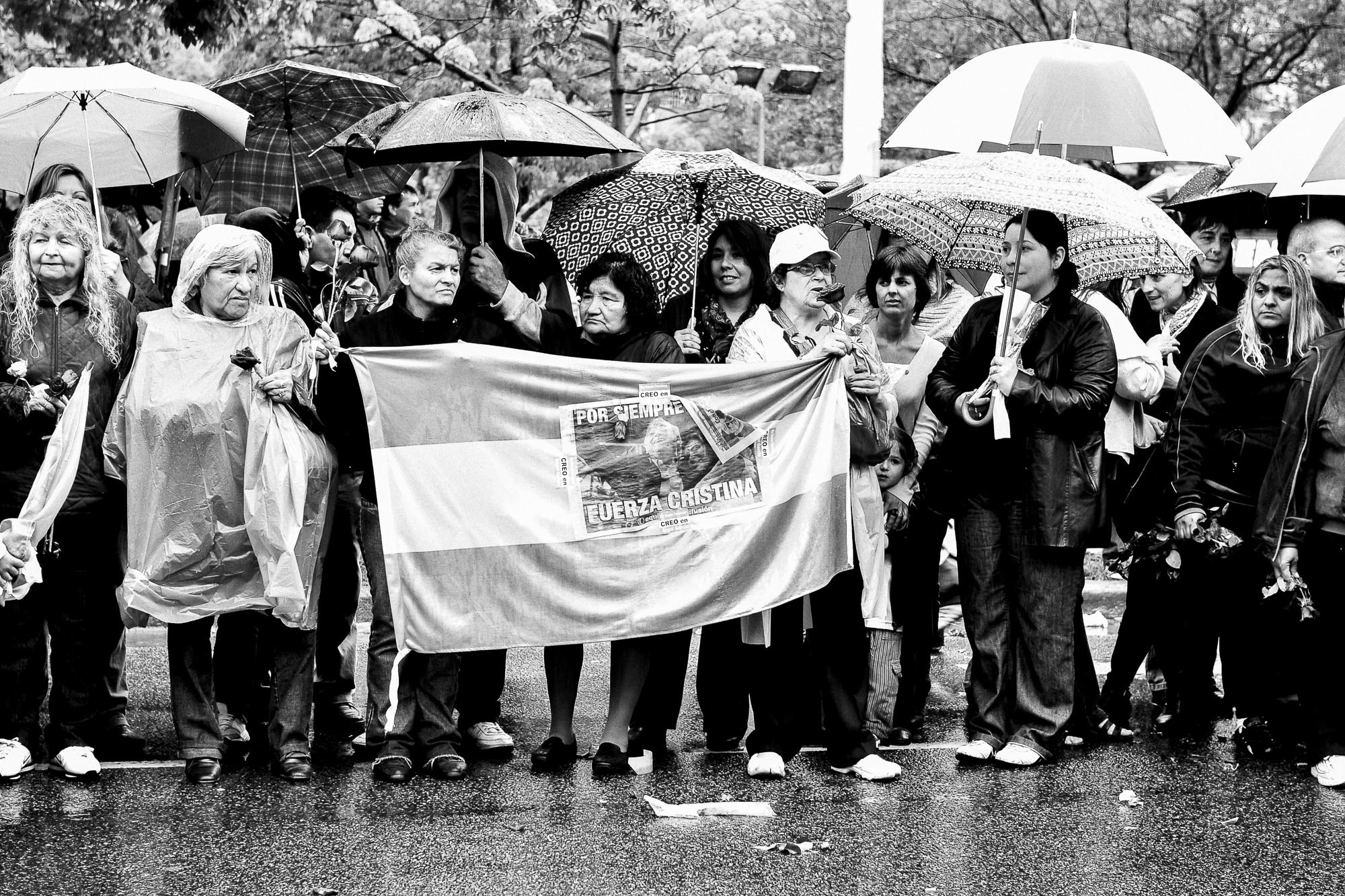 grupo de gente en la calle con paraguas y bandera de argentina