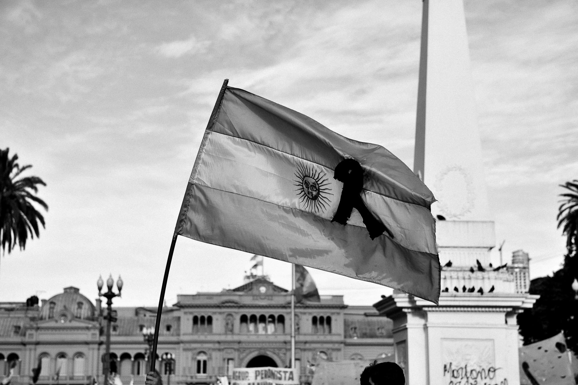 bandera argentina con la cinta de luto en primer plano y la casa rosada de fondo