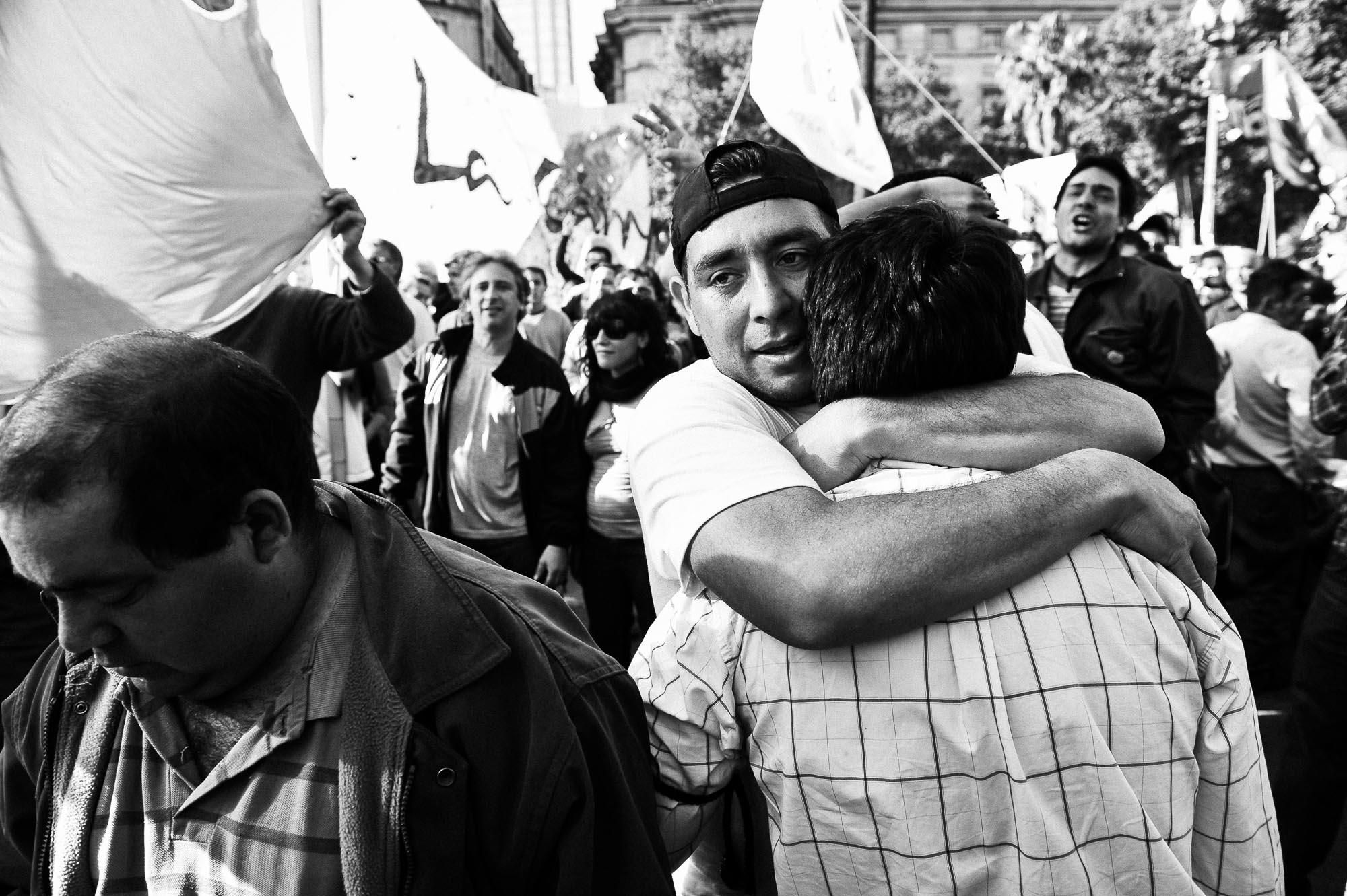 dos hombres se abrazan entra la multitud en las calles de buenos aires