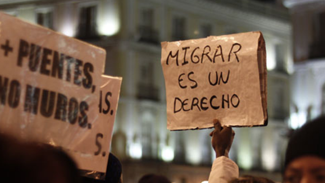 una persona sostiene un cartel con la leyenda migrar es un derecho