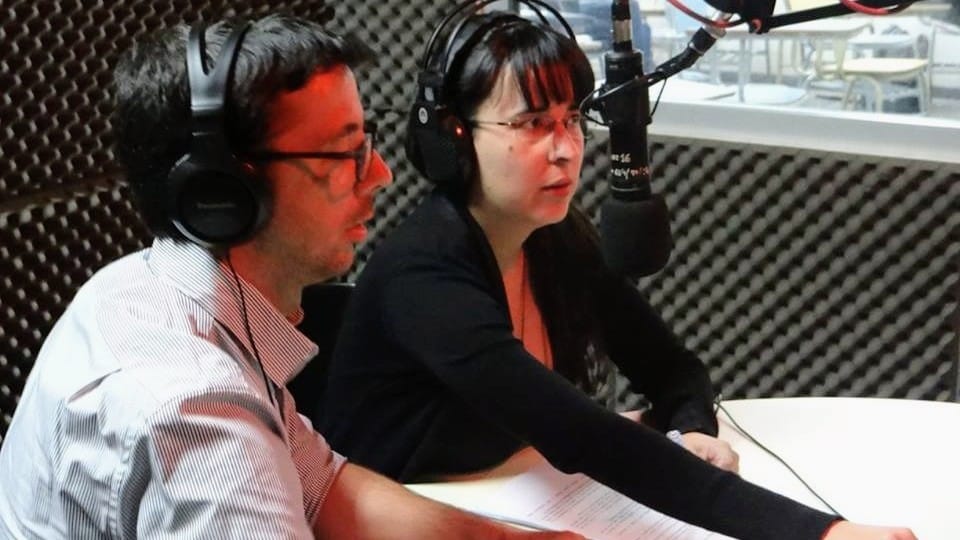 Dos personas frente a un micrófono en un estudio de radio